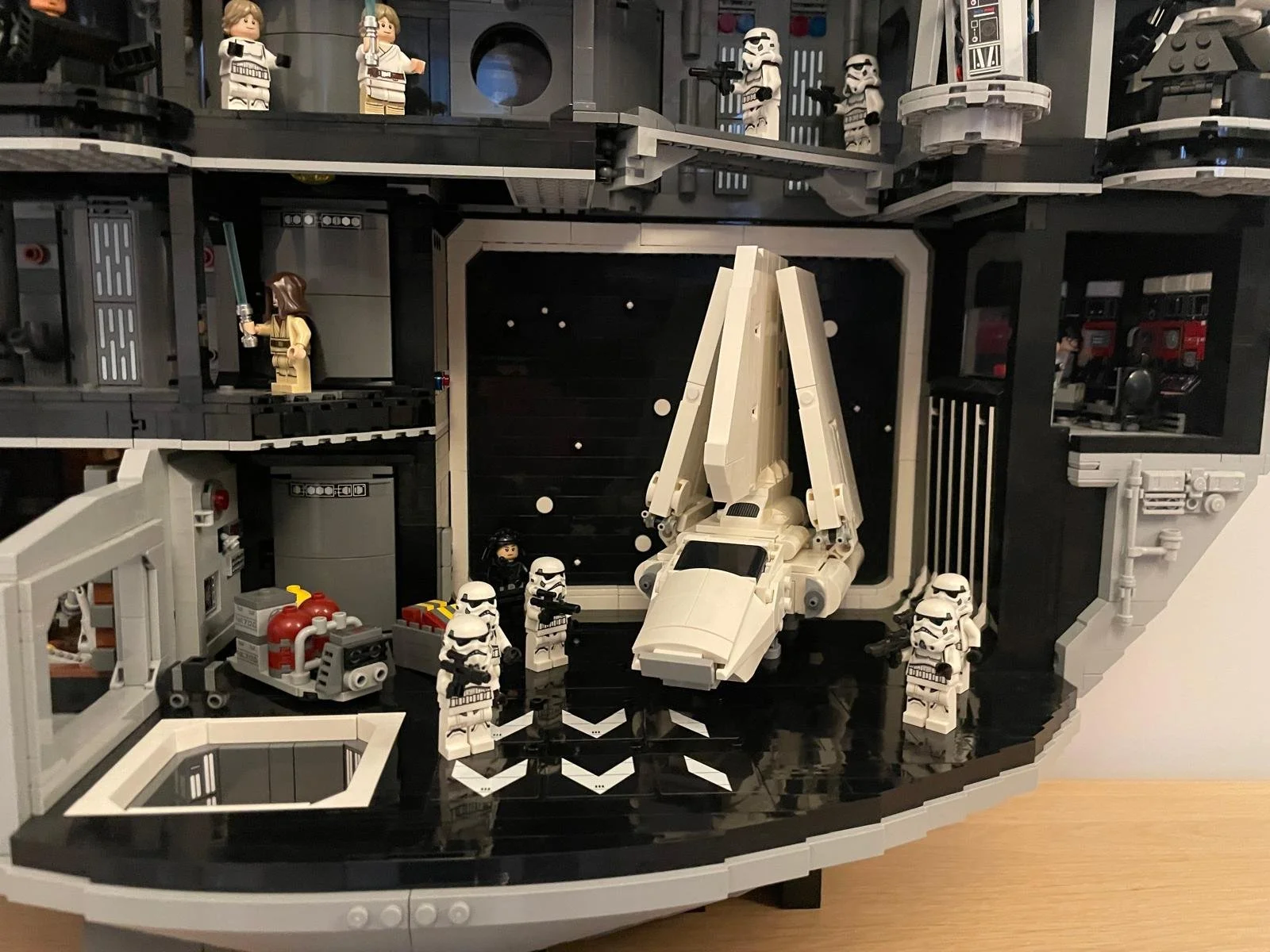 LEGO Star Wars scene featuring a LEGO Millennium Falcon spacecraft surrounded by LEGO Stormtroopers, with a LEGO Darth Vader minifigure near the spacecraft, set inside a detailed LEGO Star Wars playset.