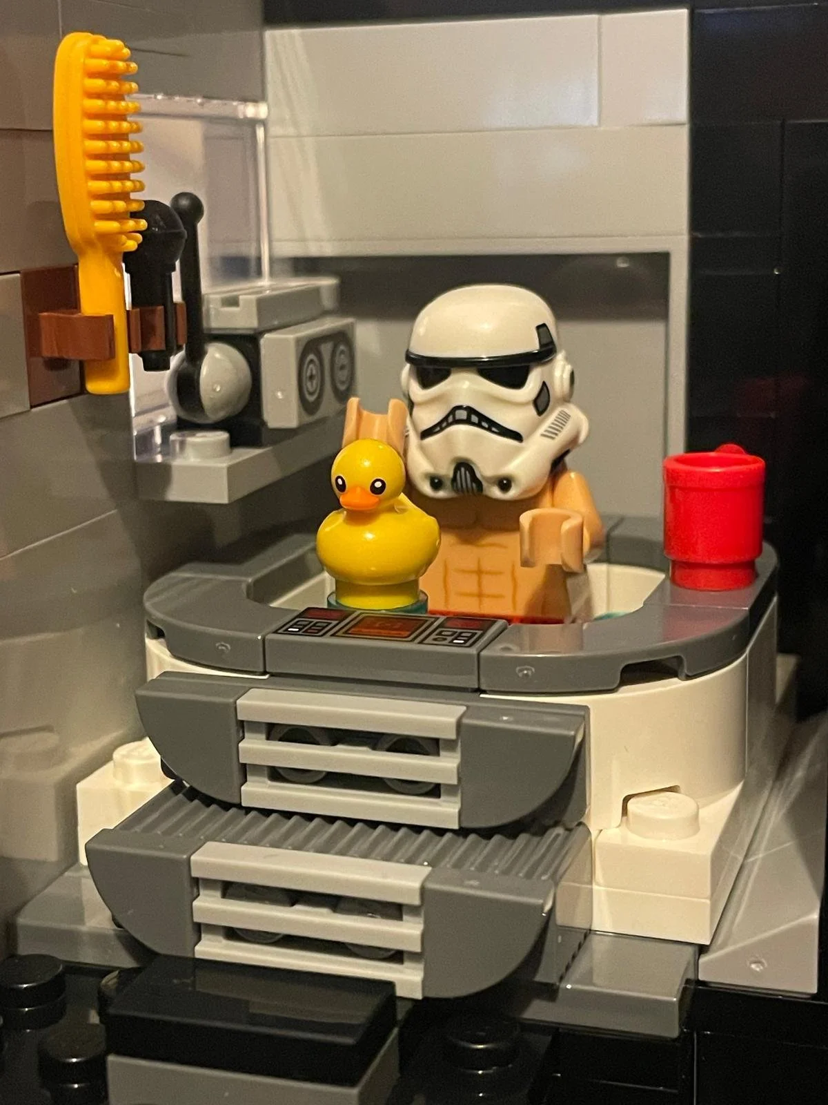 LEGO building depicting a LEGO stormtrooper minifigure with a rubber duck in front, inside a LEGO kitchen scene with various LEGO accessories and structures.
