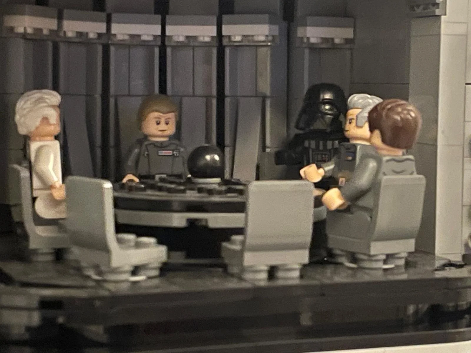 Lego scene depicting a star wars meeting inside the Death Star conference room with five Lego characters, including Darth Vader, Princess Leia, and other officers.