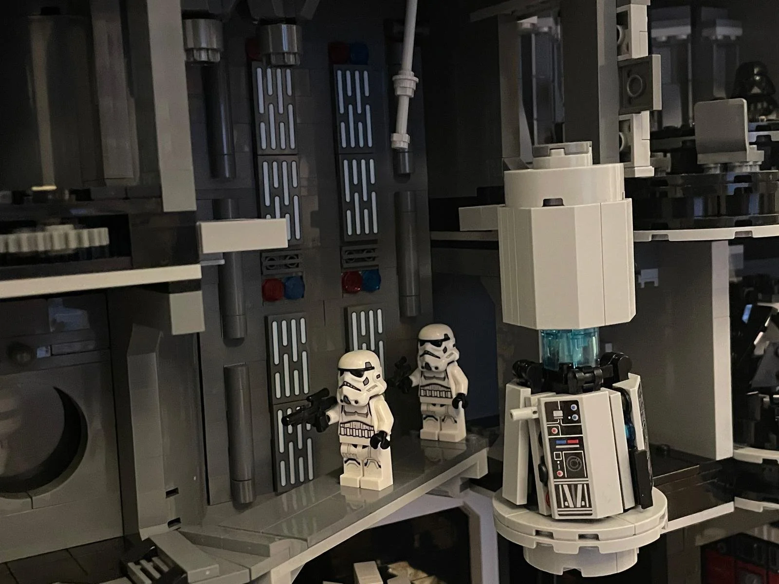 LEGO Star Wars scene with two stormtrooper minifigures holding guns, set against a detailed gray spaceship interior with control panels and machinery