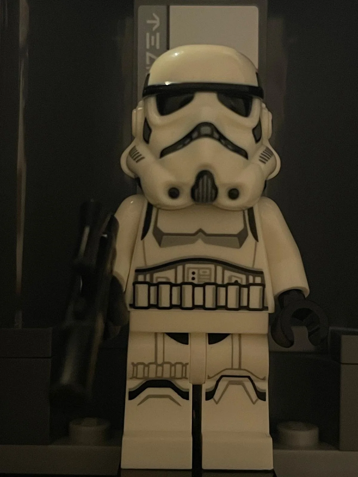 Lego Stormtrooper minifigure standing with a black weapon in his right hand.
