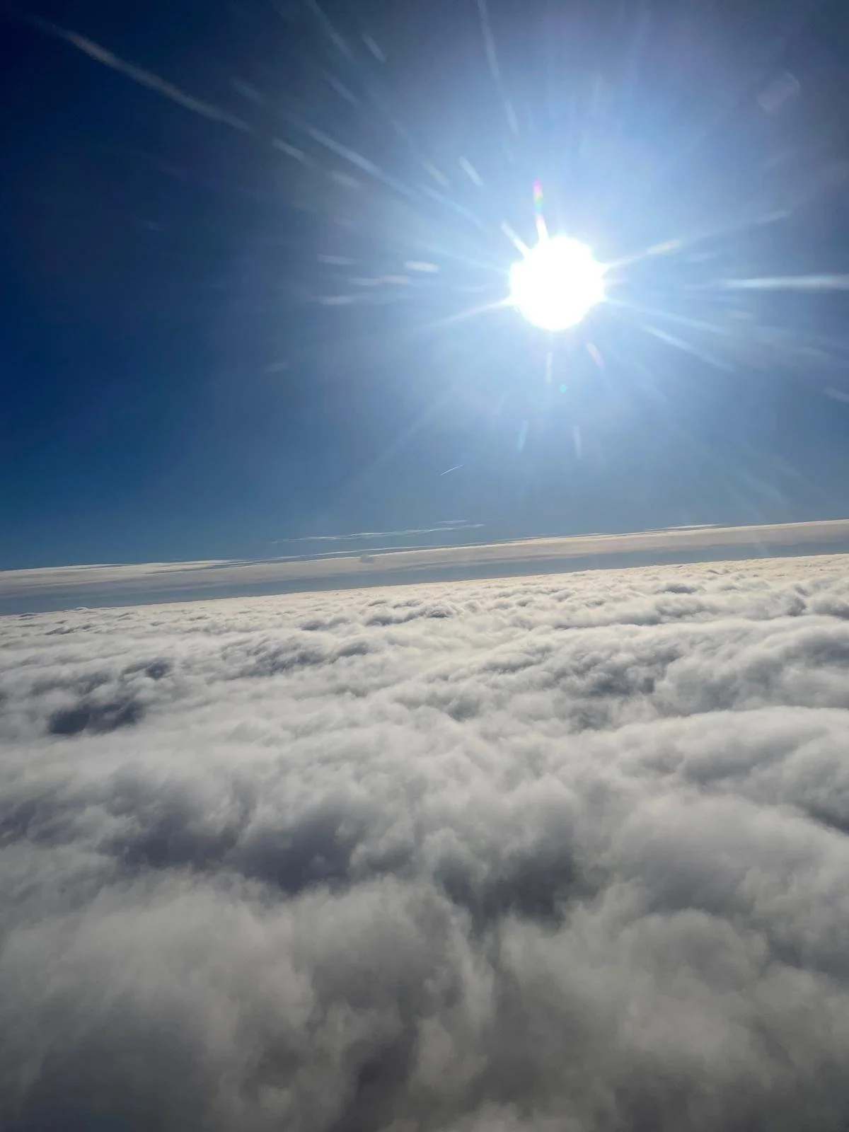 View of the sky above the clouds with a bright sun shining and clear blue sky.