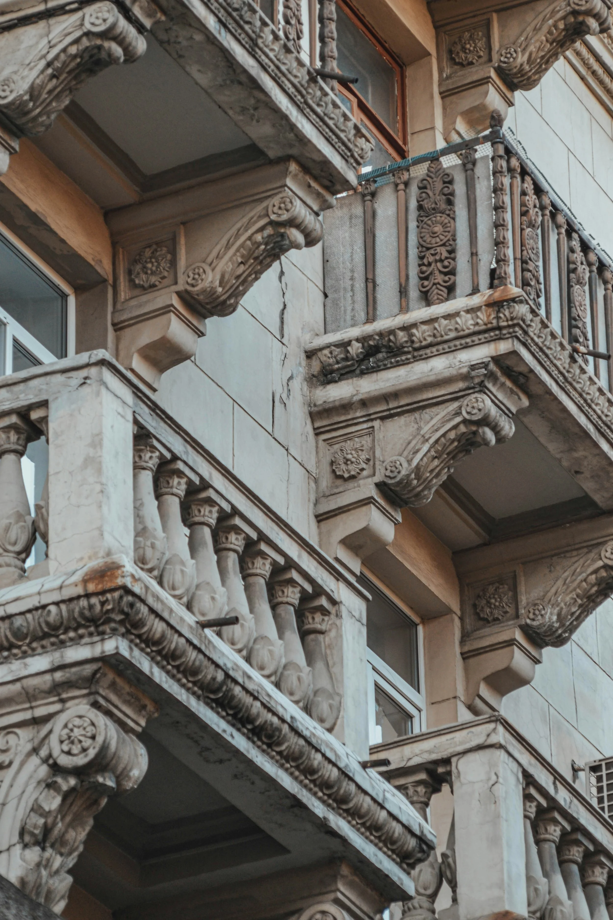 Ein altes Gebäude mit kunstvoll verzierten Steinfassaden und Edelmetallgeländern auf den Balkonen, typisch für historische europäische Architektur.