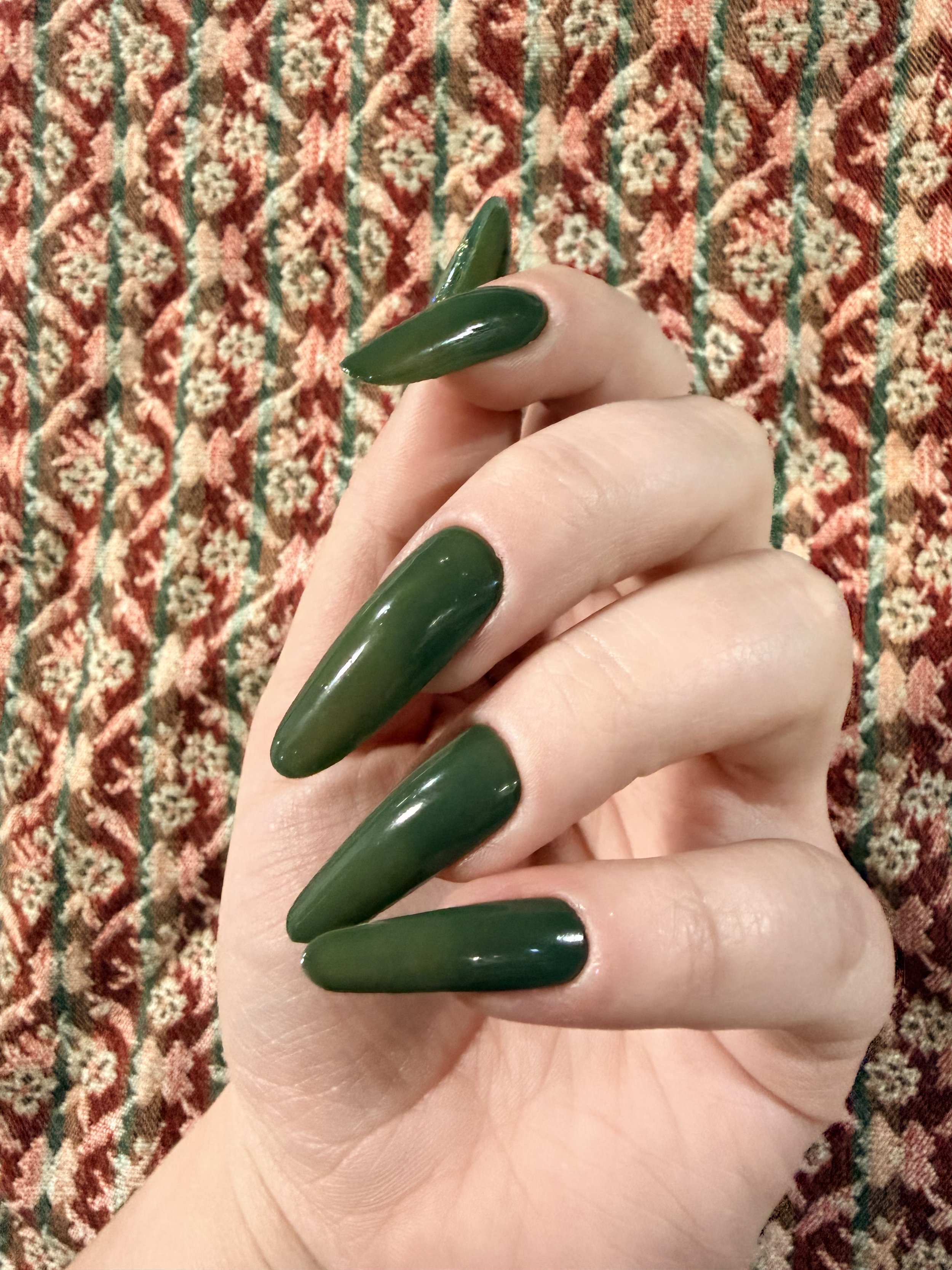 Unlearning whole hand - green polish with tapestry in background | Boldly Nail Polish