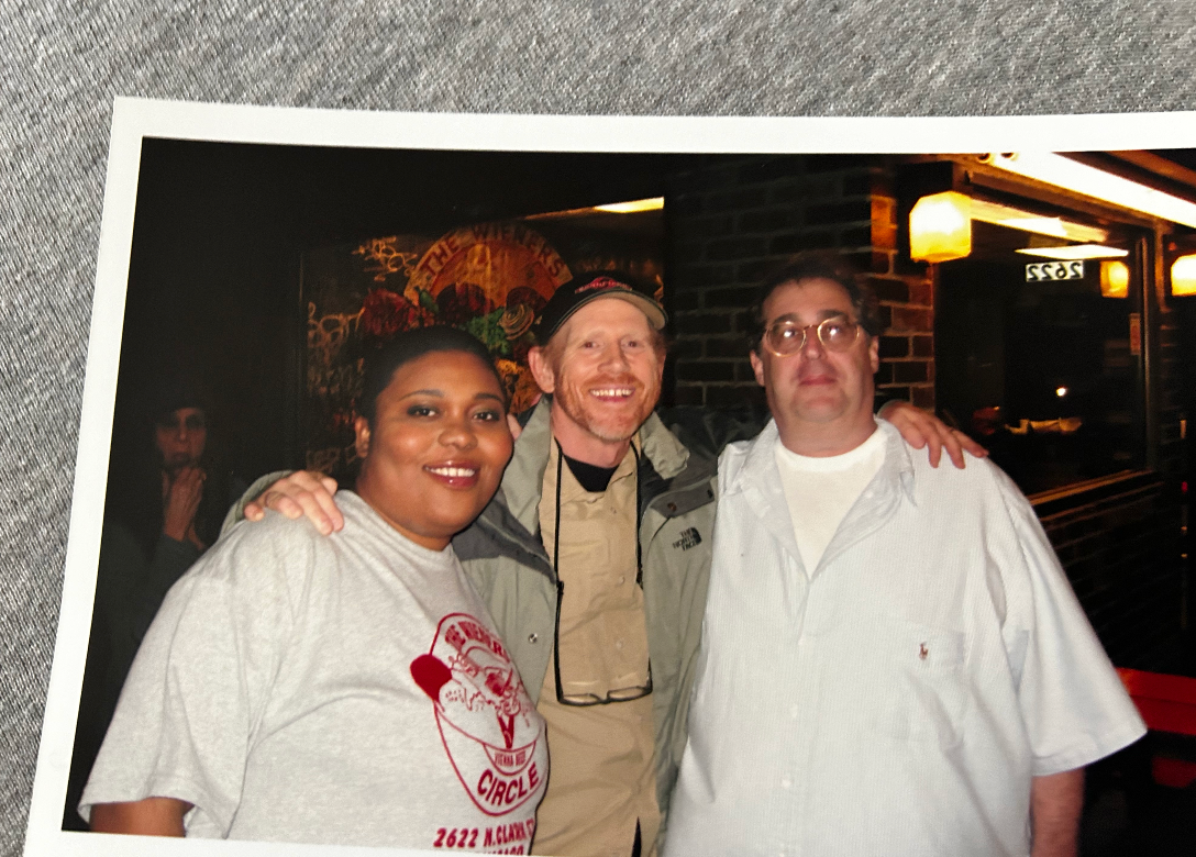 Three people smiling and posing together outside a building at night
