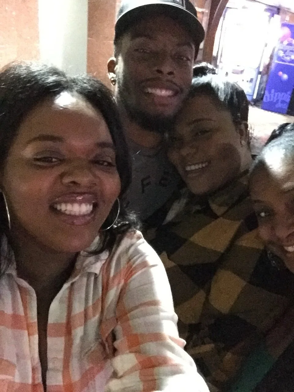 A group of five friends smiling and taking a selfie together at night in an indoor setting.