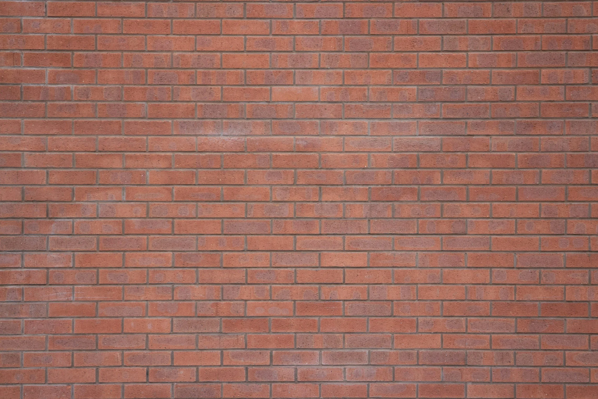 A red brick wall with evenly spaced bricks and mortar.
