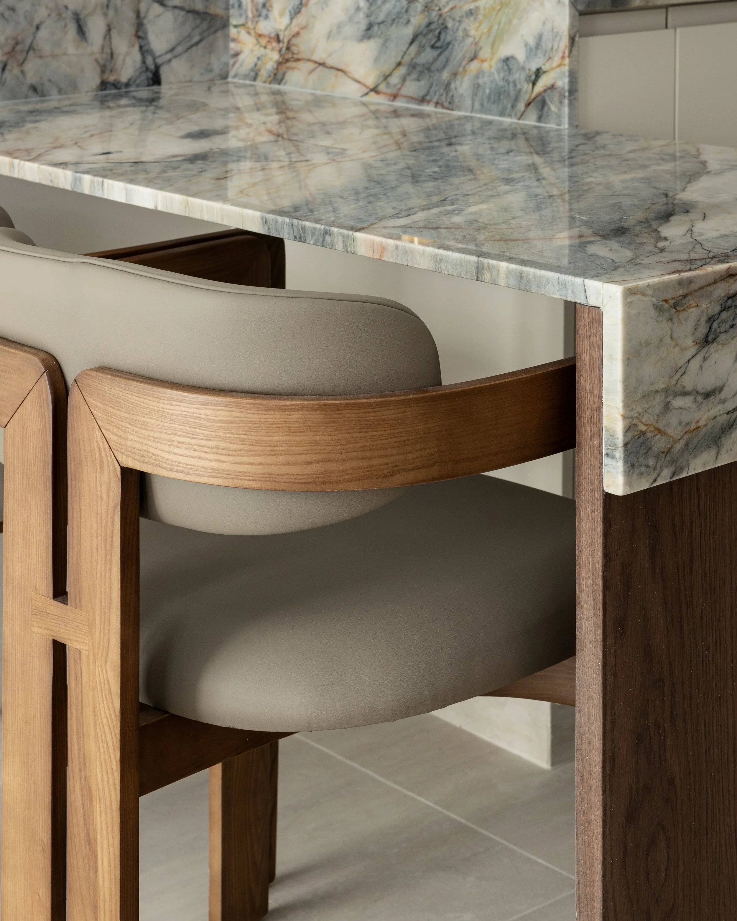 Close-up view of a marble dining table with chairs, highlighting the marble's natural veining and polished surface.