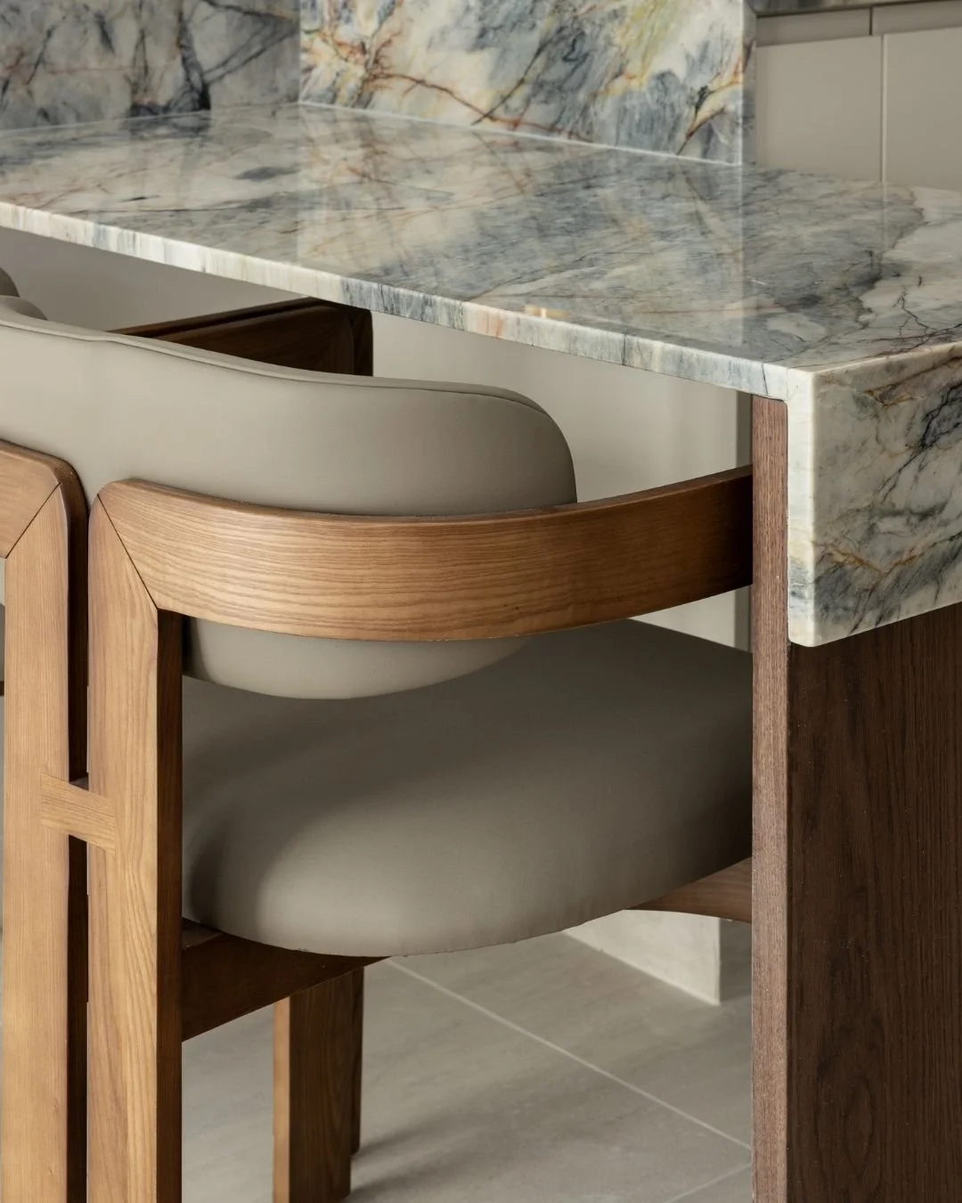 Close-up of a marble dining table with wooden and upholstered chairs underneath.