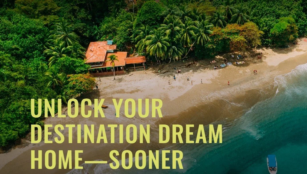 Aerial view of a tropical beach with clear water, sandy shore, lush green trees, and a house with a red roof nestled among the trees.
