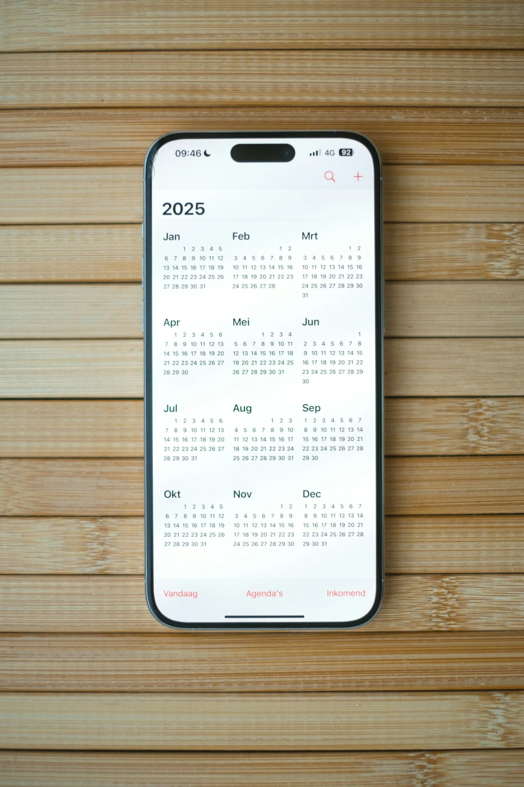 A smartphone displaying a 2025 calendar on a wooden surface.