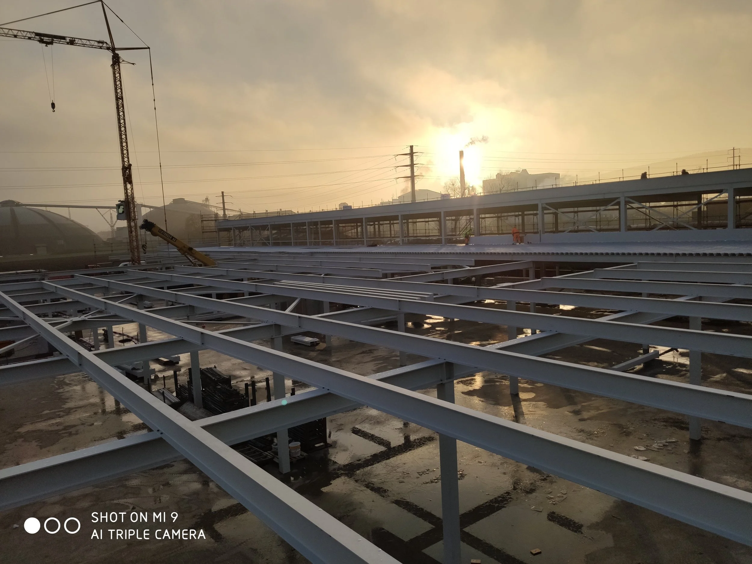 Baustelle mit Stahlträgern und Baugerüst bei Sonnenaufgang