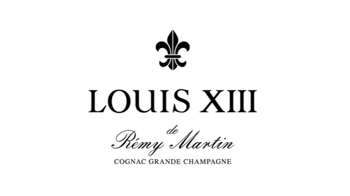 Label for Louis XIII cognac, featuring a fleur-de-lis symbol and elegant black serif and cursive fonts on a white background.
