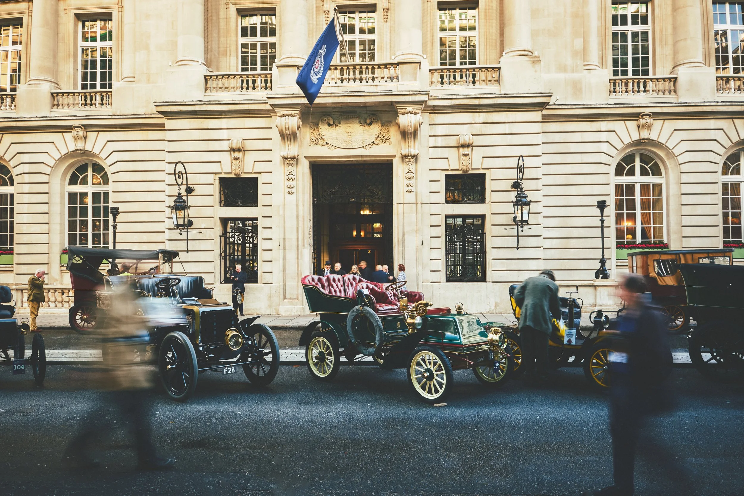 Historic building with ornate facade, people, and vintage carriages on the street.