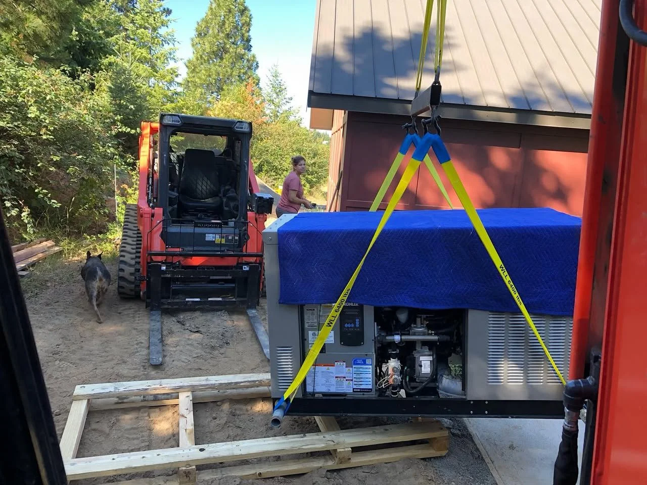 A skid steer and excavator being used to set a 24KW Kohler Generator.