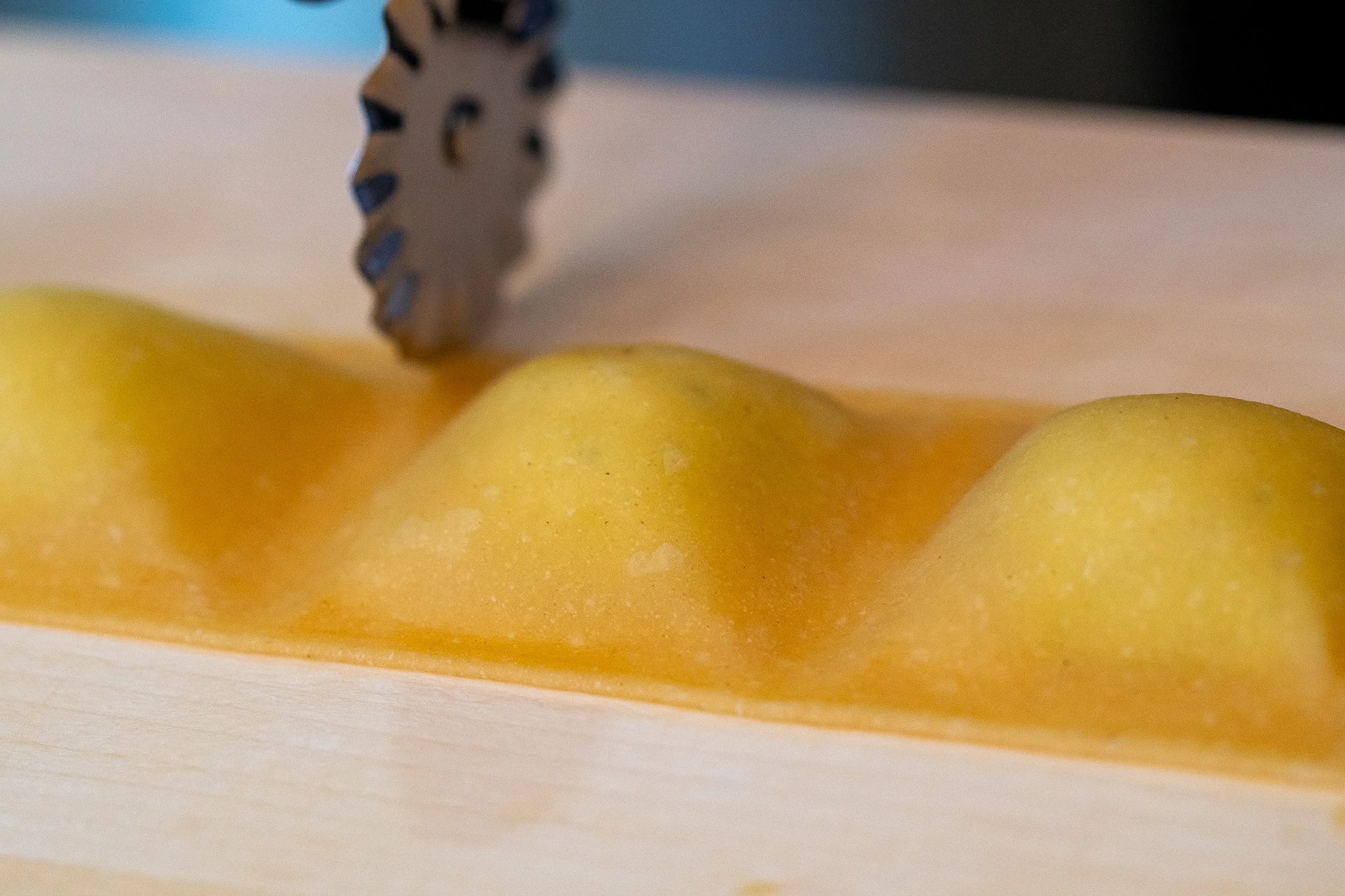 A close-up view of a yellow apple being sliced with a serrated knife on a wooden cutting board.