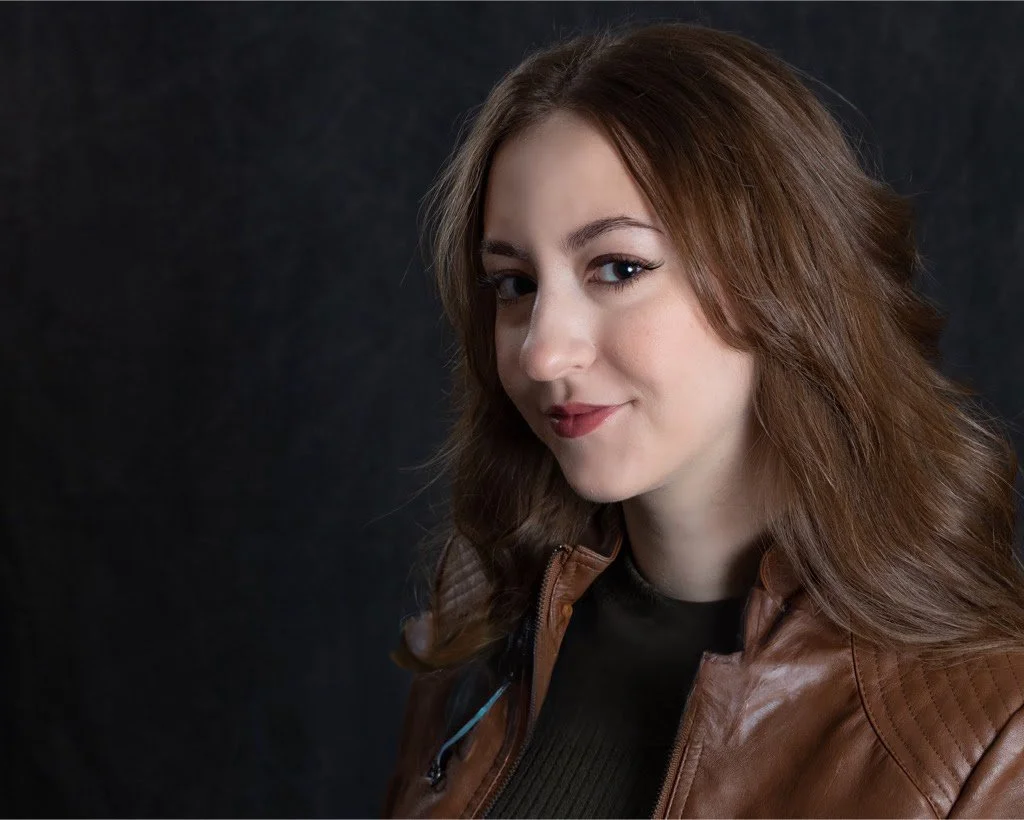 Jiana Casazza, a young actress with long, wavy brown hair posing against a dark background.
