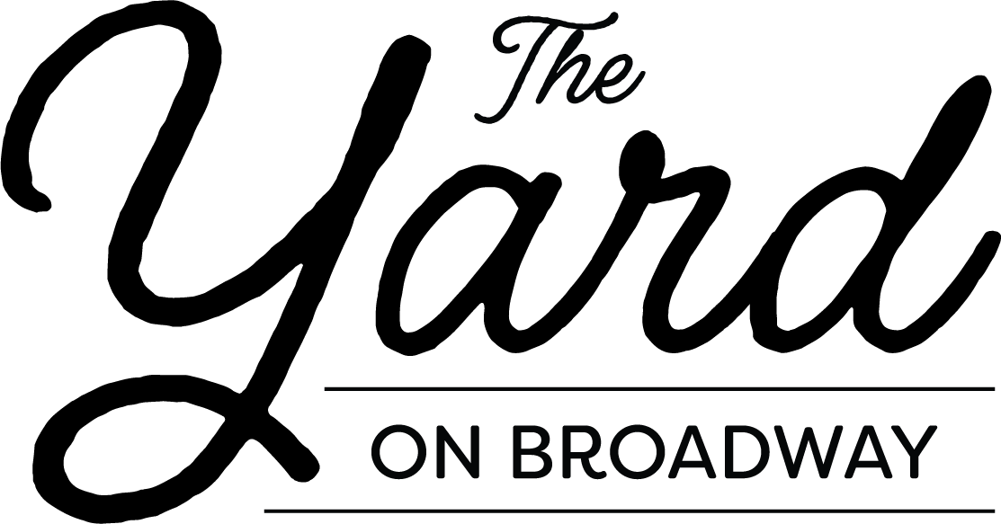 Black and white sign with the text "The Yard on Broadway" in cursive and bold font.