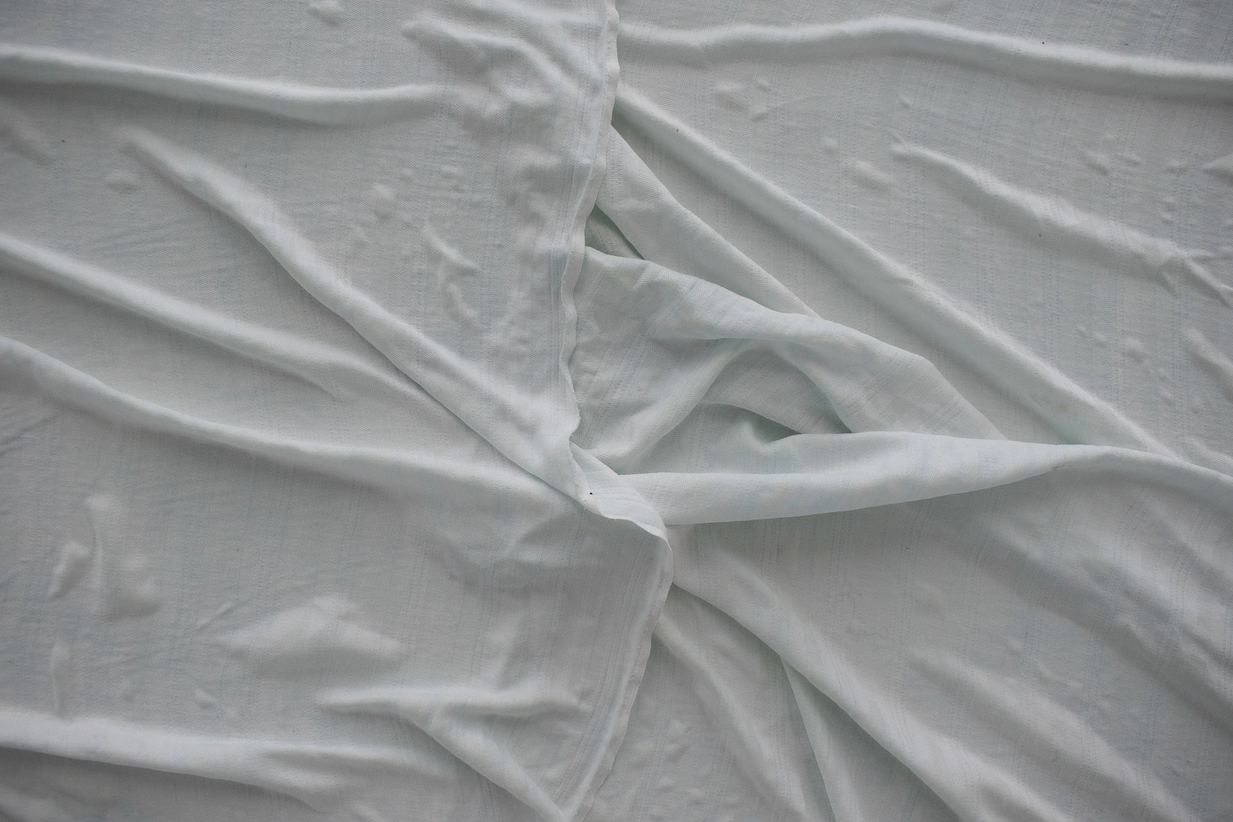 Ein weißer Stoff liegt zerknüllt auf einer Oberfläche neben einem großen runden Gegenstand.