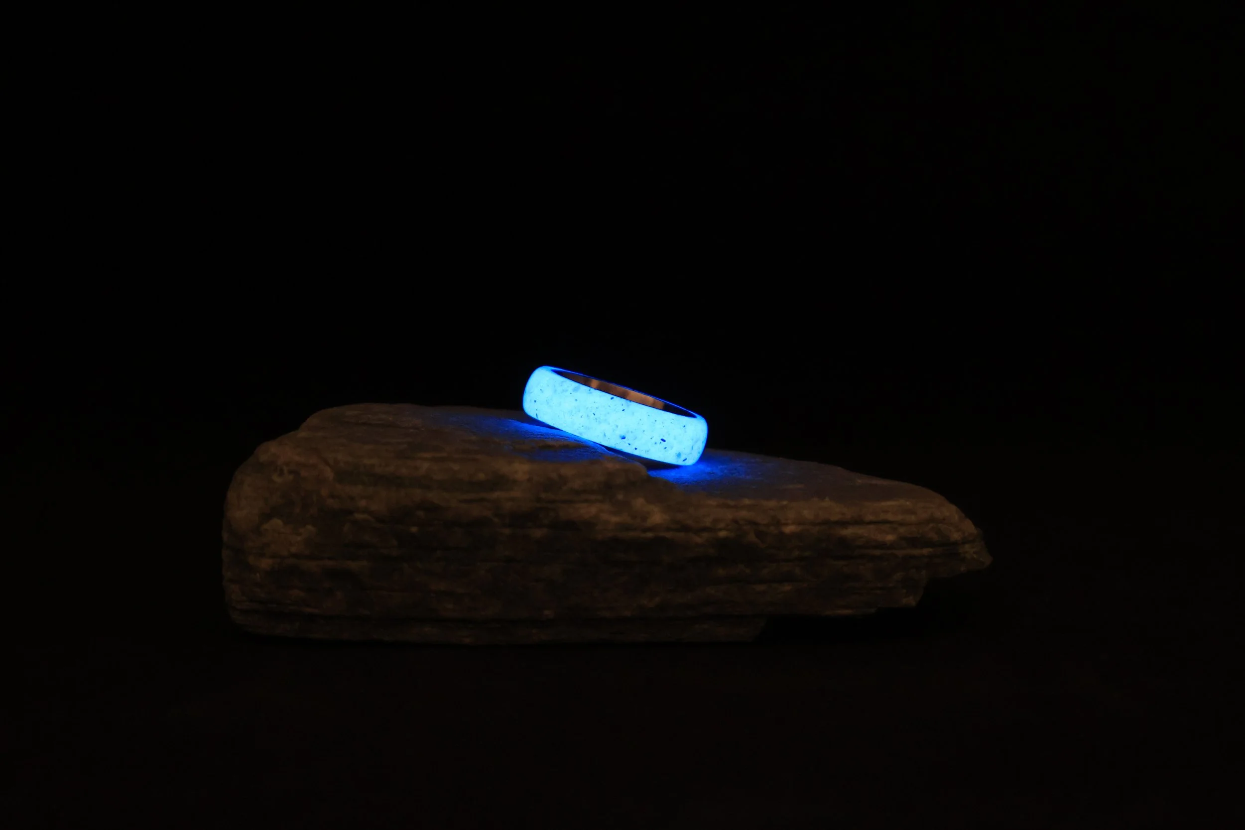 Ein leuchtender blauer Ring liegt auf einem Stück Holz gegen einen schwarzen Hintergrund.