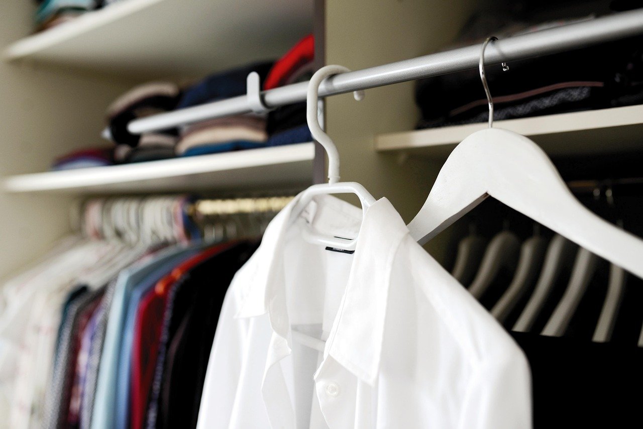 Closet with a hanging white shirt on a hanger, other clothing items blurred in the background.