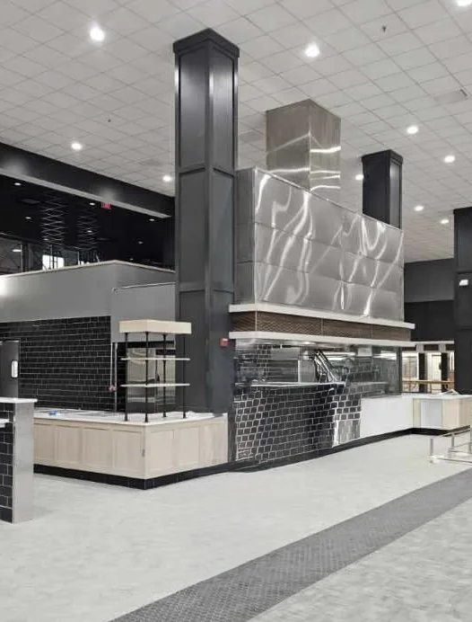 Interior of a modern cafeteria or dining area with black and white tile accents and metal fixtures.