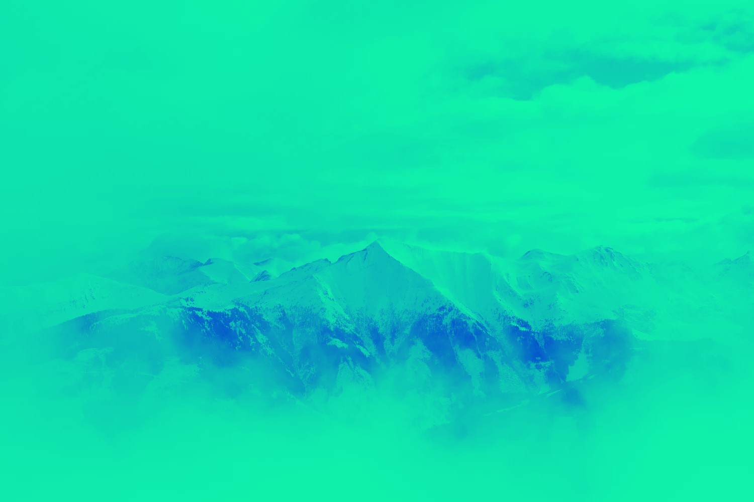 Snow-covered mountain range under a mostly cloudy sky.