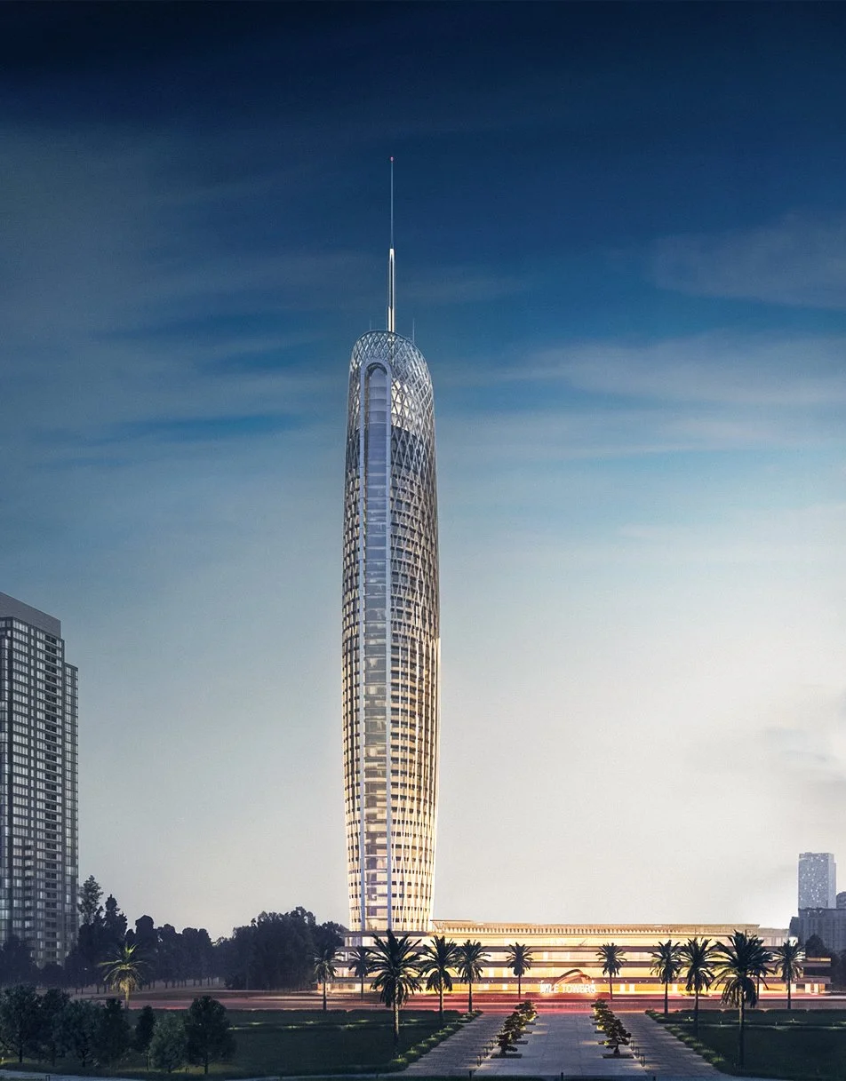 A tall modern skyscraper with a rounded, lattice-like facade against a blue sky with wispy clouds, surrounded by palm trees and other buildings.