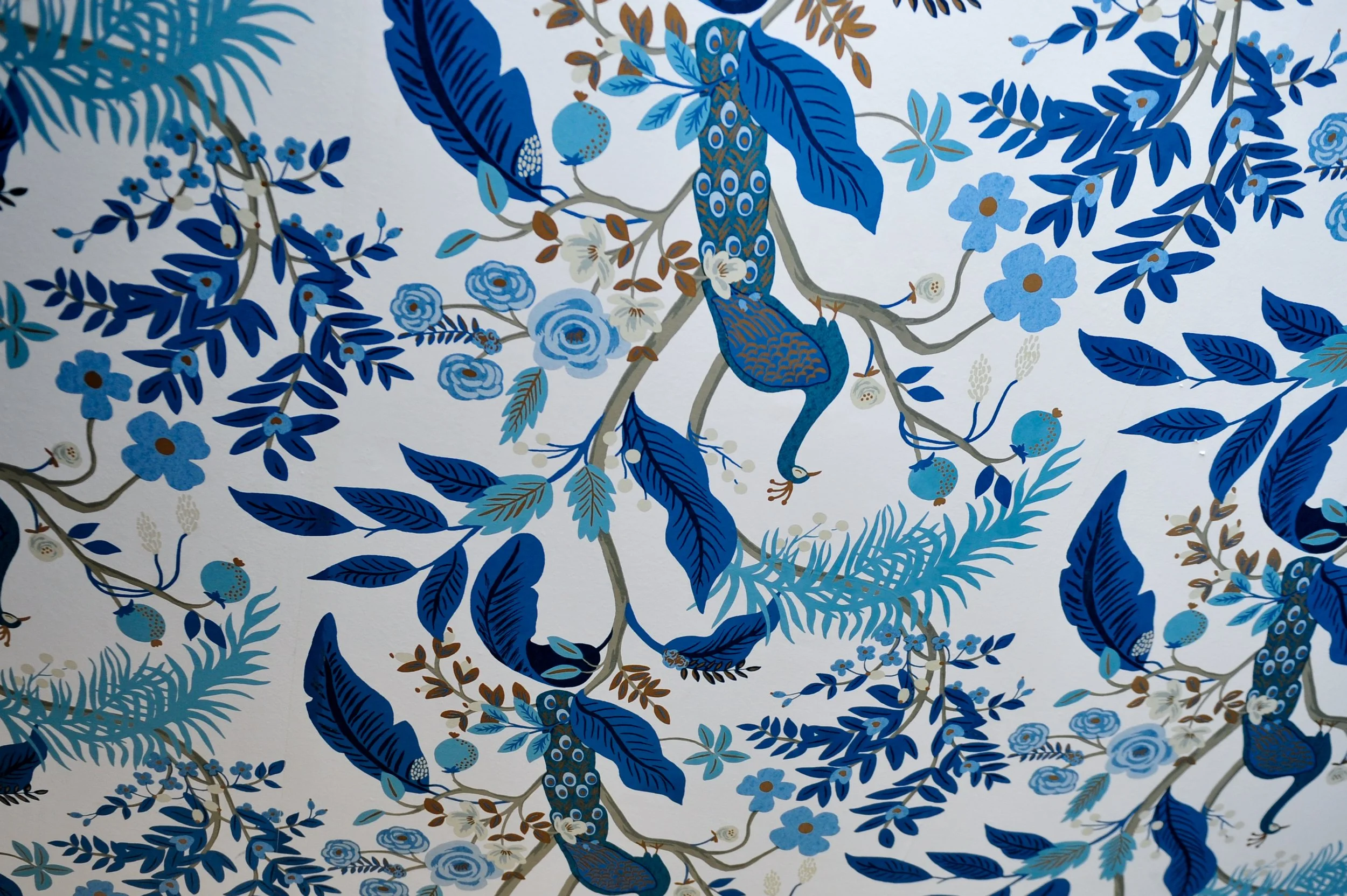 A decorative wallpaper with blue and gold floral and bird pattern.