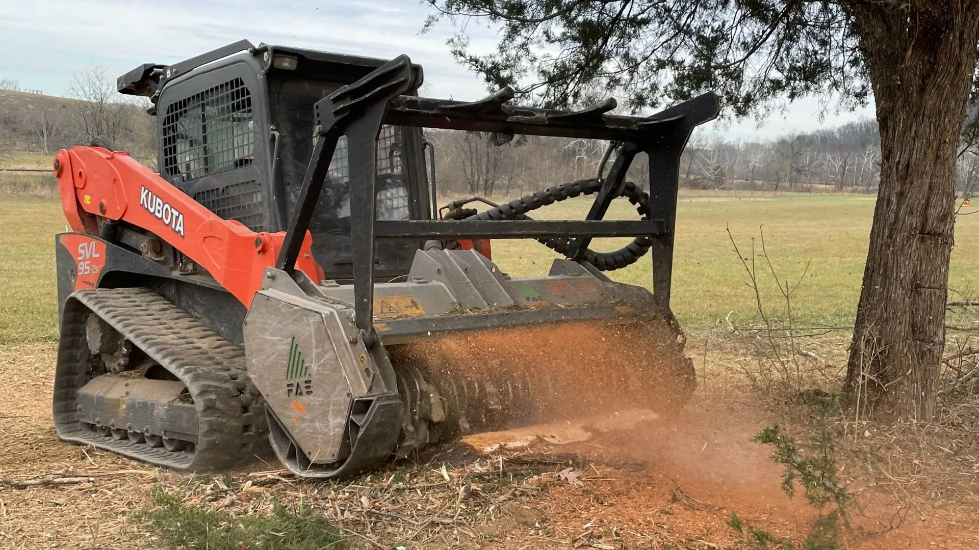 A Forestry Mulcher clearing trees and brush in an open field.