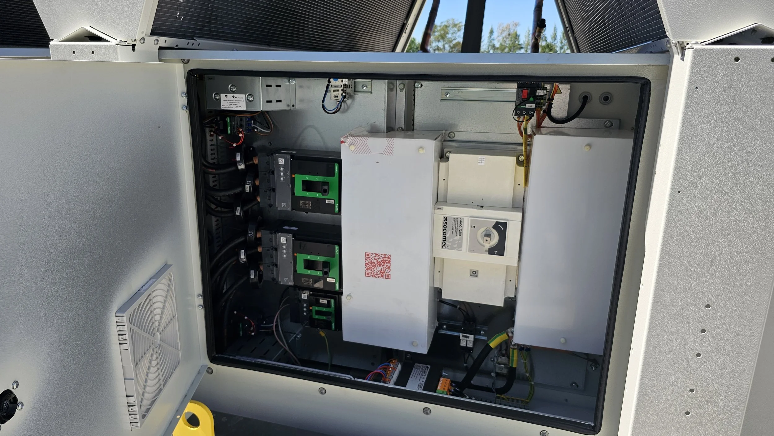 Interior de un painel eléctrico con componentes electrónicos, cables y disyuntores, en un gabinete metálico abierto.