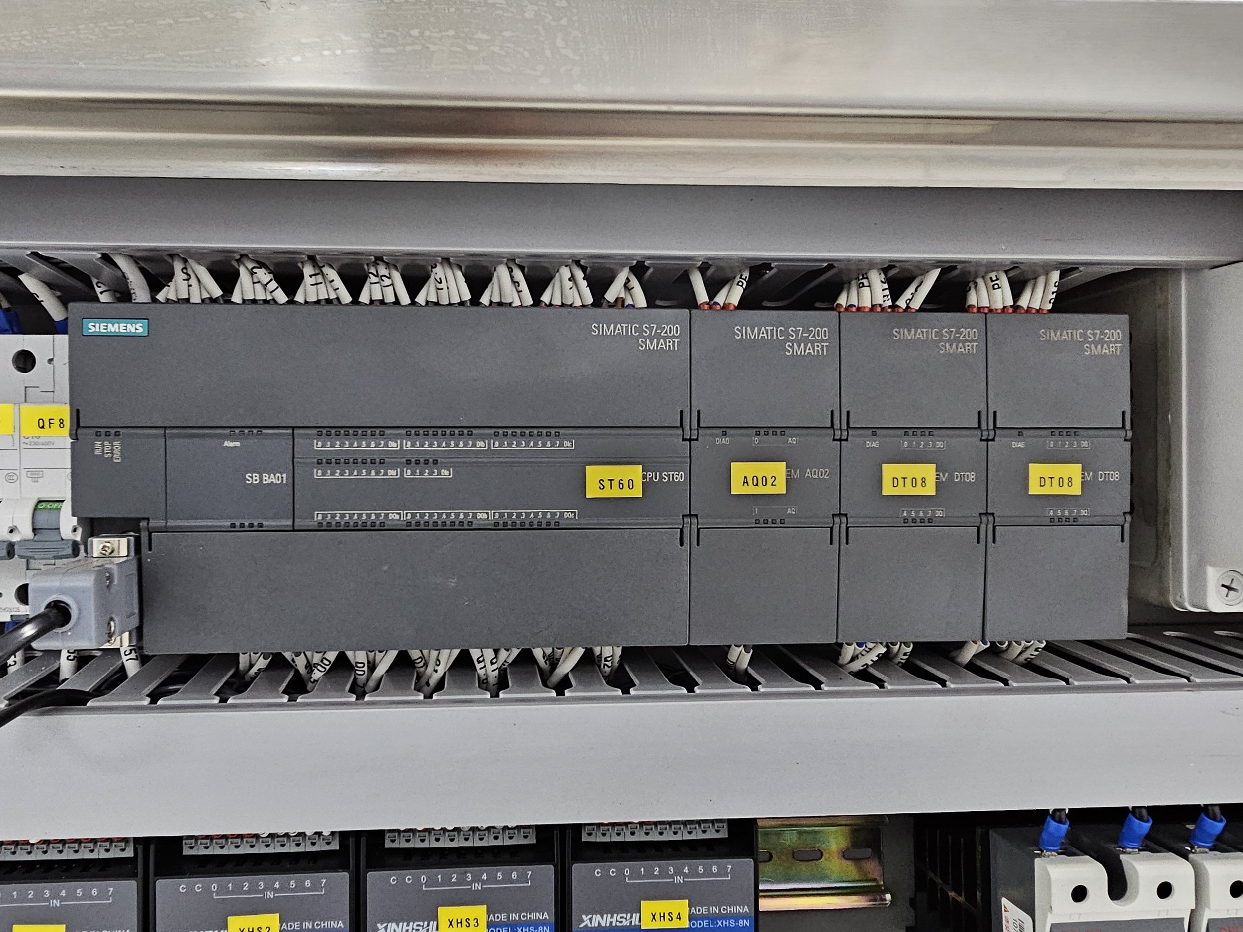 Caja de control con componentes Siemens, etiquetas y cables electrónicos en un panel de automatización industrial.