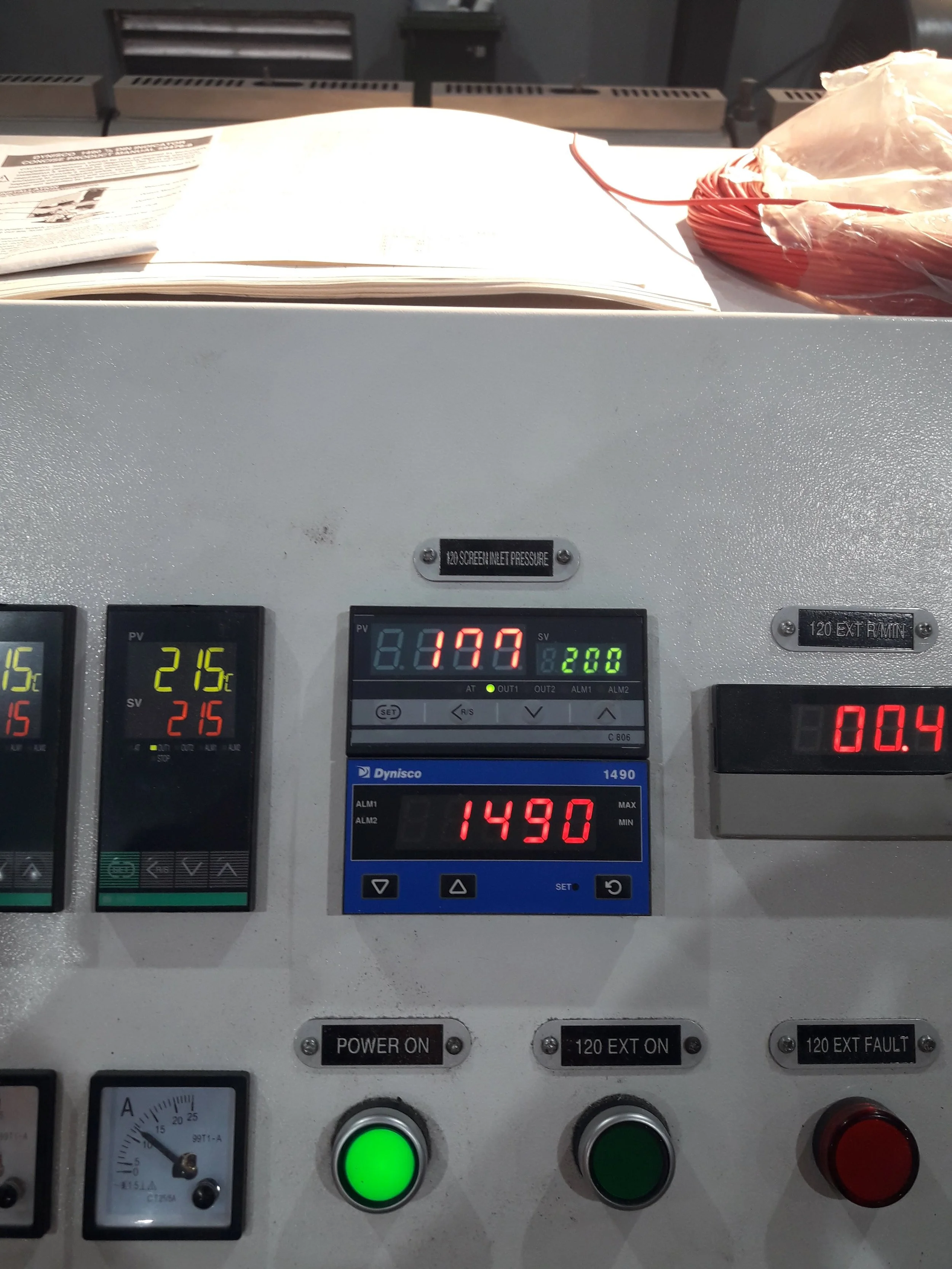 Pantalla y controles de una máquina industrial con números y luces, en un entorno de control técnico.