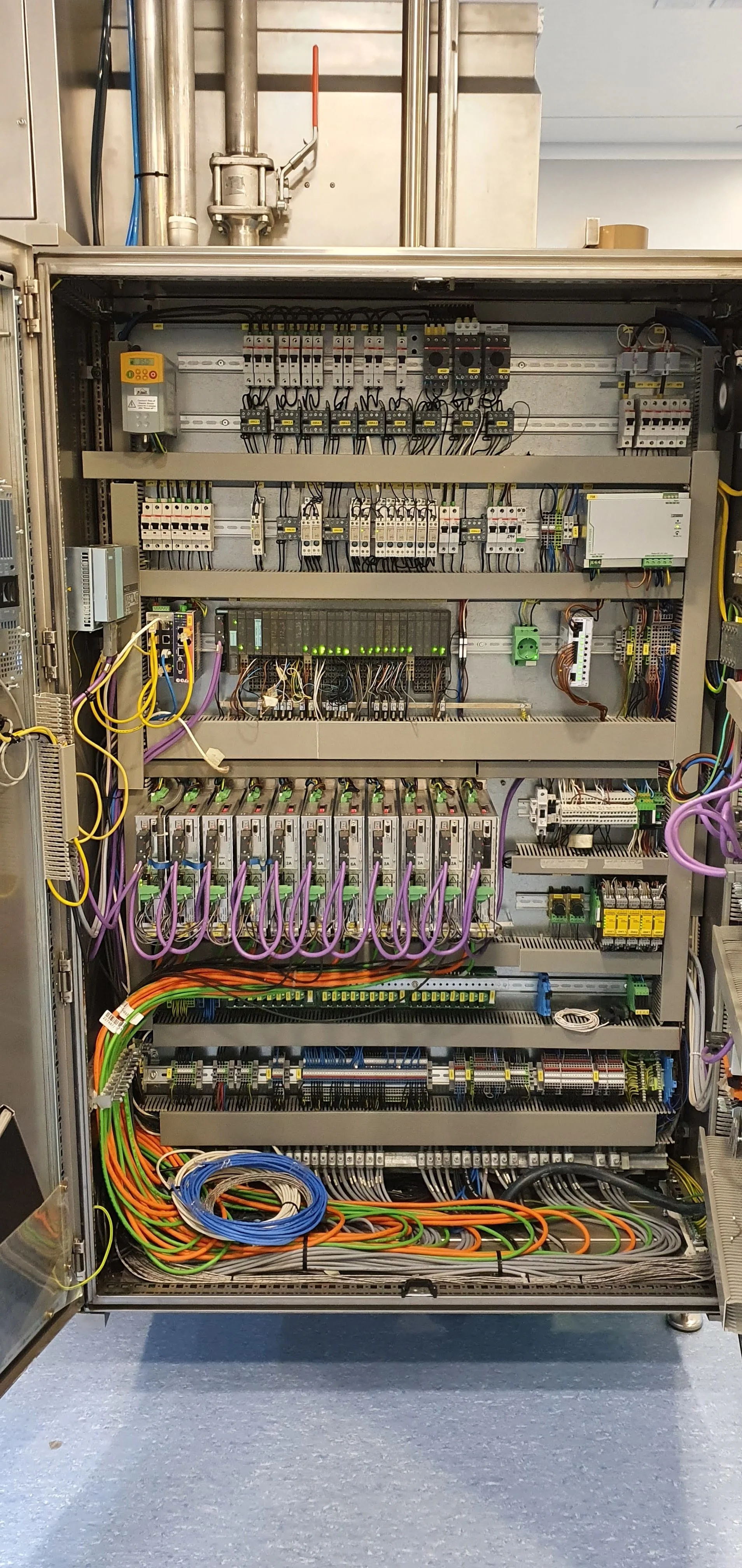 Panel de control eléctrico con componentes y cables organizados en un gabinete de Automatización industrial.