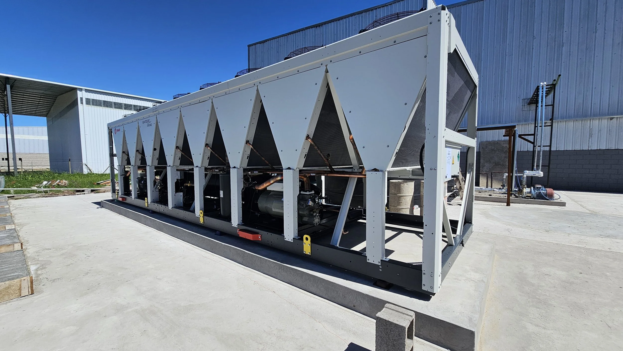 Unidad de aire acondicionado grande instalada en exterior, con componentes visibles y estructura metálica