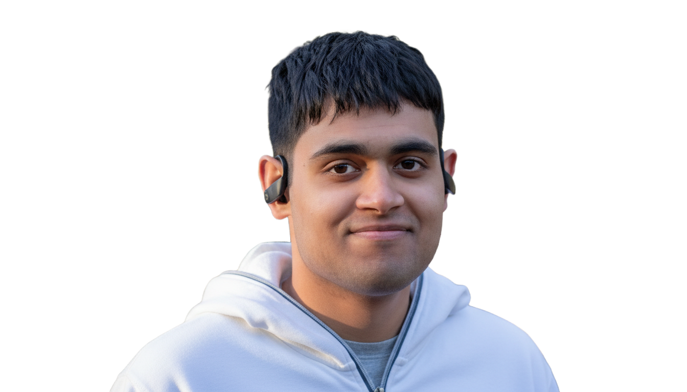 A young man with short black hair wearing a white hoodie and wireless earbuds, smiling at the camera.