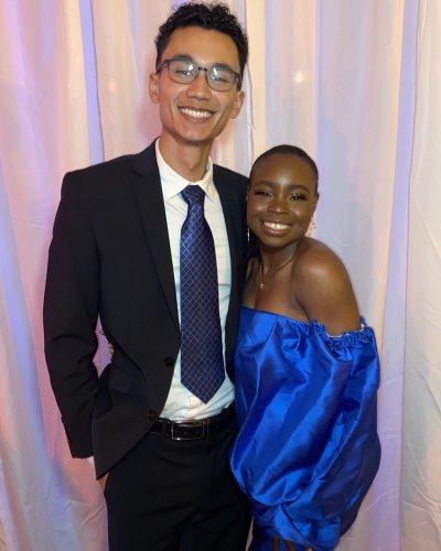 Mope and Robert smiling together at an event, standing in front of white curtains. 