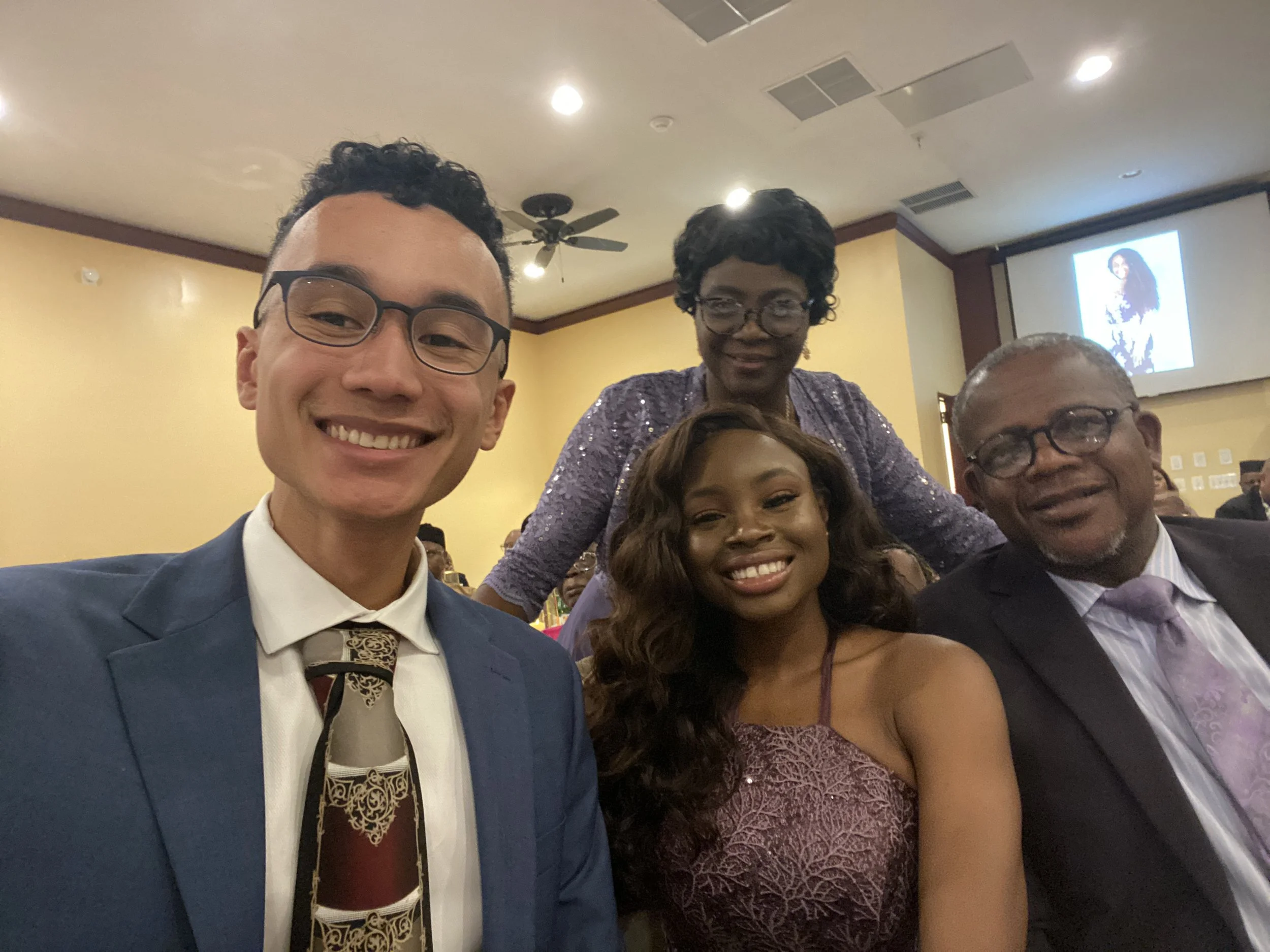 Robert and Mope dressed formally, smiling, at indoor event with Mope's parents.