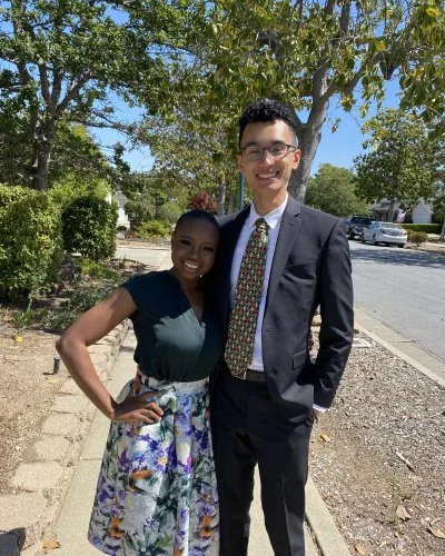 Mope and Robert standing outside on a sidewalk under trees.