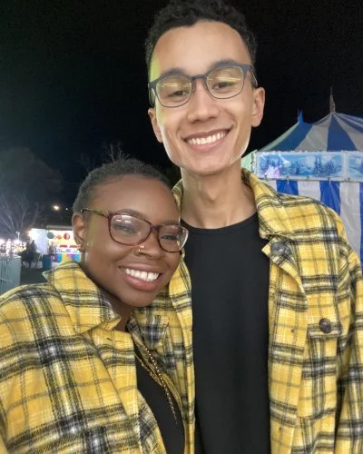 Robert and Mope smiling, wearing matching yellow plaid shirts at an outdoor event.