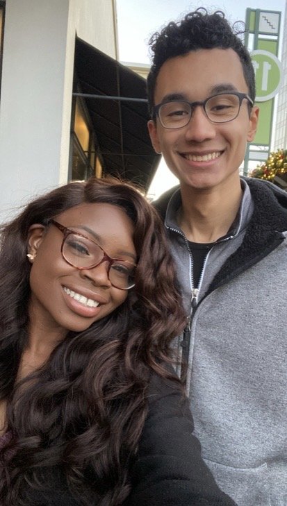 Mope and Robert taking a selfie outside a building on a cloudy day. 