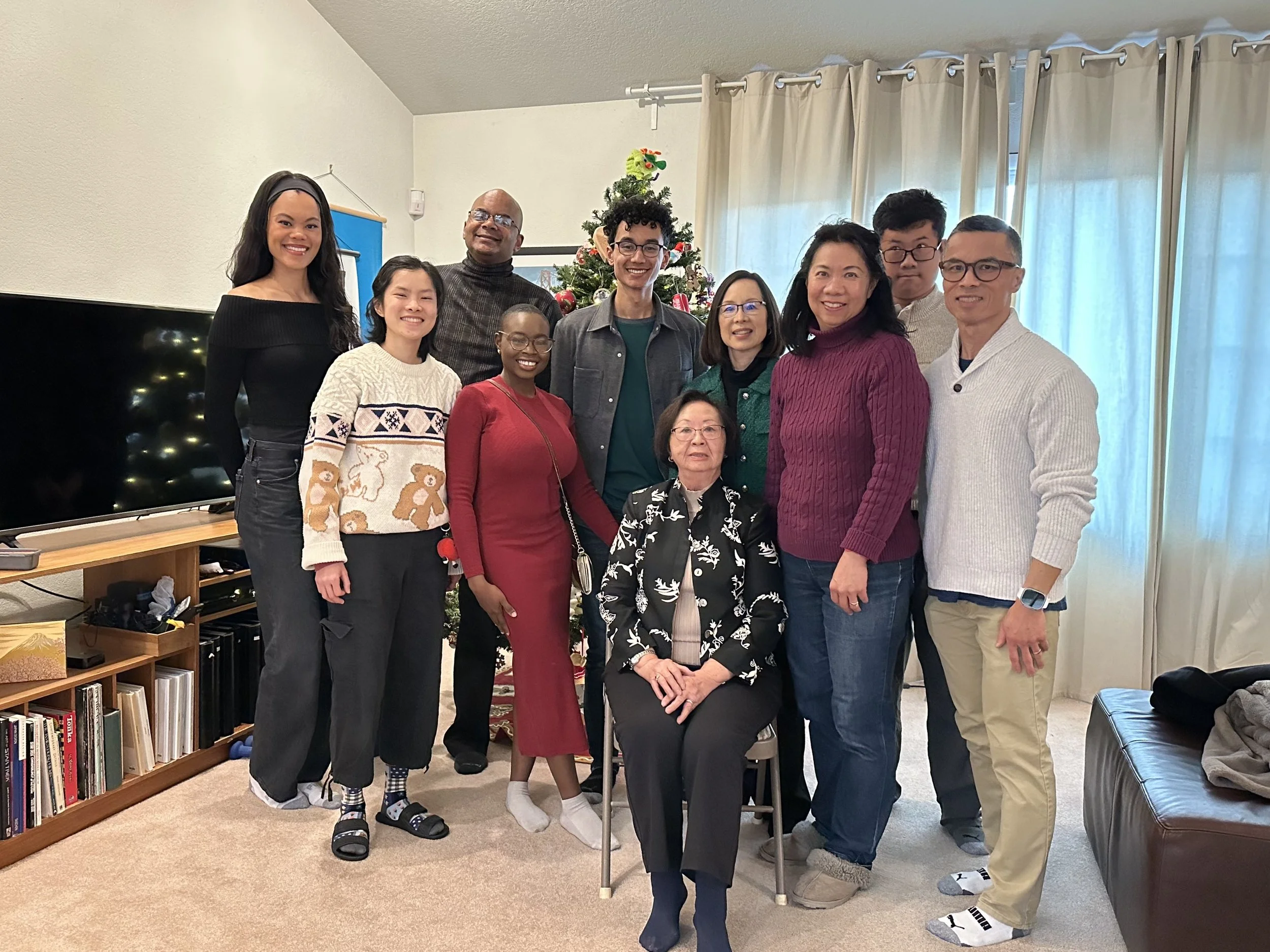 Robert and Mope gathered with Robert's family in a living room around a decorated Christmas tree, smiling for a photo.