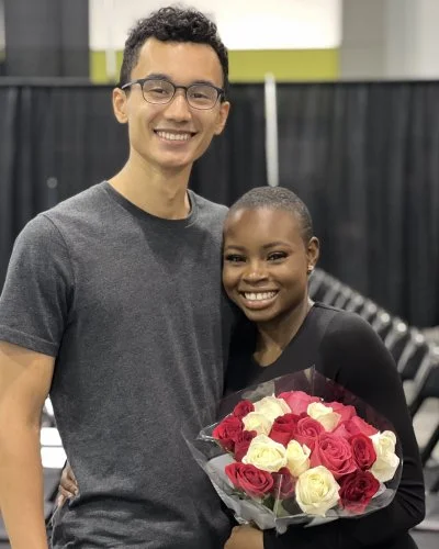 Robert and Mope smiling, with the Mope holding a bouquet of red and white roses.