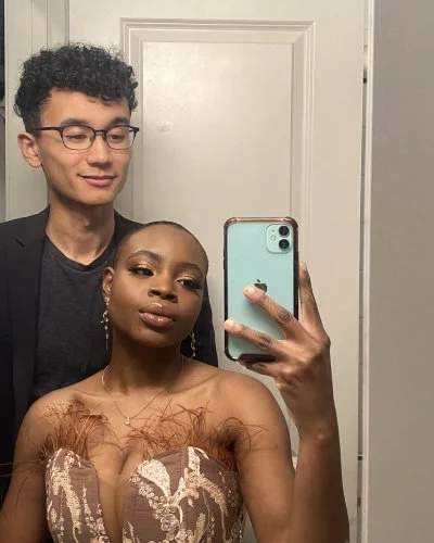 Mope taking a mirror selfie with Robert standing behind her in a bathroom.