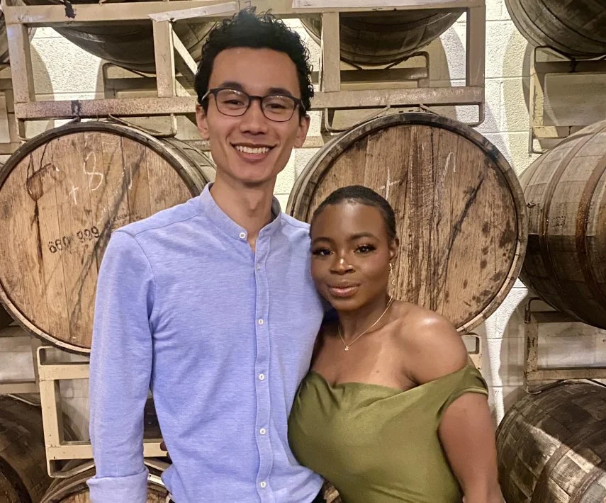 Robert and Mope standing close together, with large wooden barrels in the background.