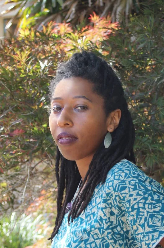 Image of artist Cindy Bonaparte facing camera surrounded by nature.