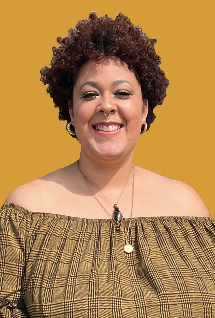 Image of artist Raina Beigler smiling at camera against a mustard background.