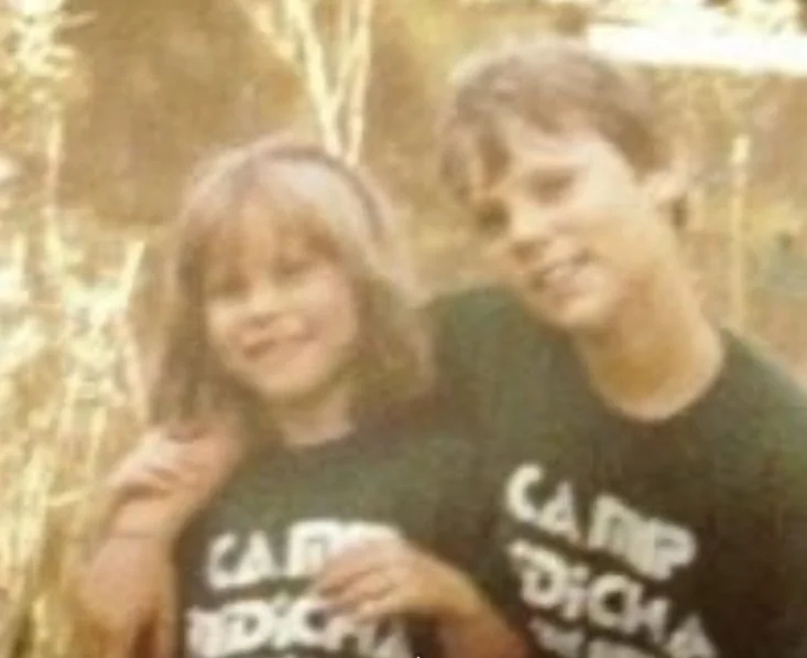 Vintage photo of two siblings standing close together in matching Type 1 diabetes camp T‑shirts, faces blurred for privacy