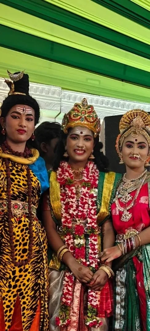 Three women in traditional Indian attire, wearing ornate jewelry and costumes, participating in a cultural celebration or festival.