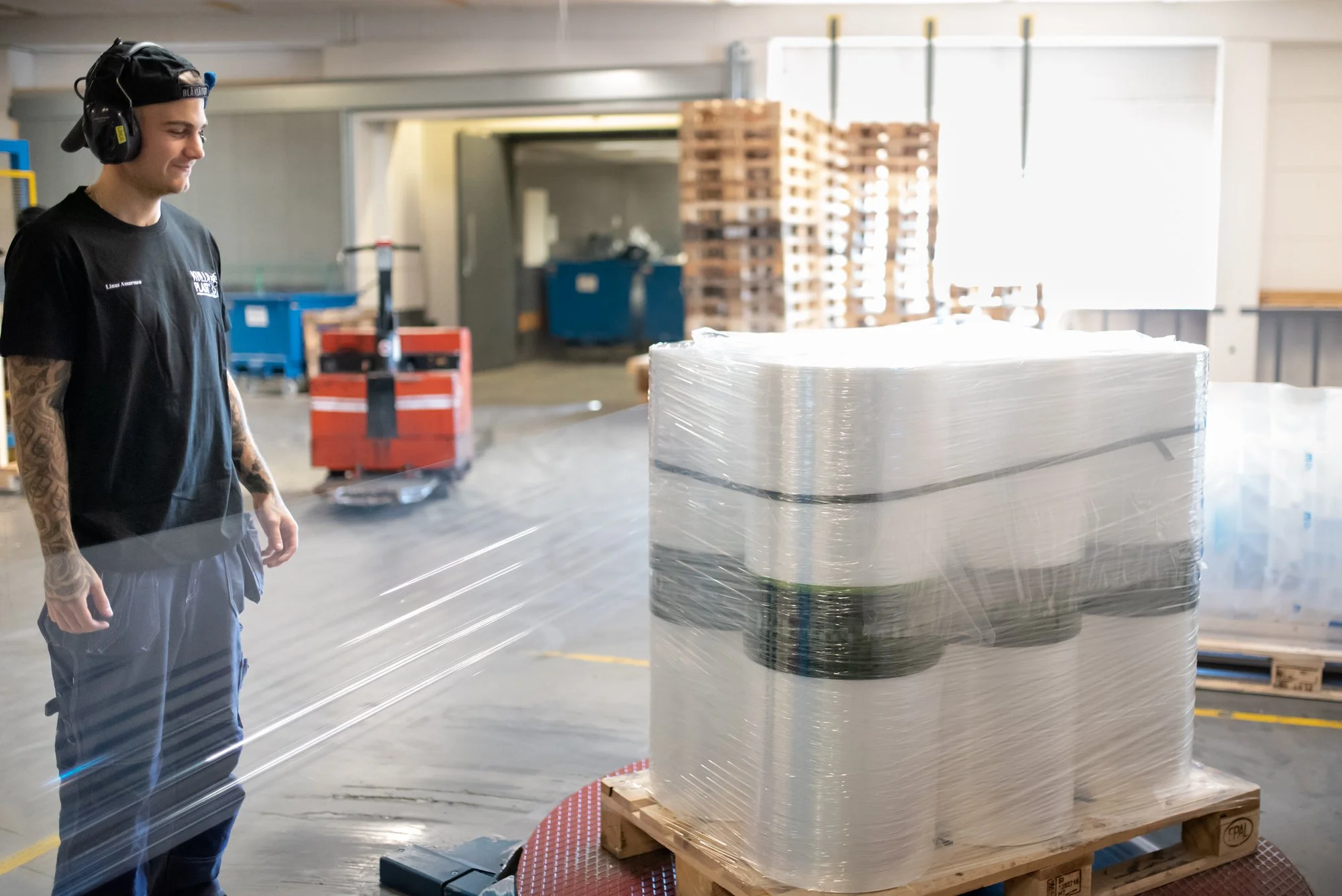 Maskinoperatör sveper en packad pall med PE-film